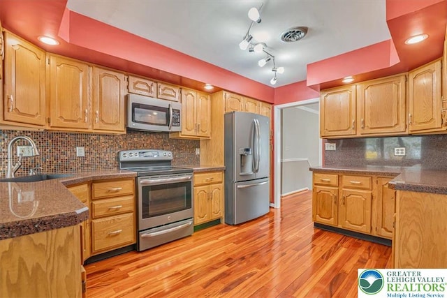 kitchen featuring tasteful backsplash, light wood-style floors, visible vents, stainless steel appliances, and a sink