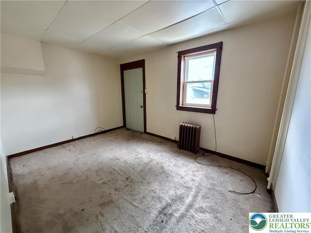 empty room featuring radiator heating unit, baseboards, and carpet flooring