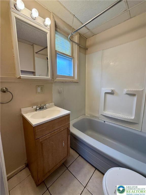bathroom with toilet, vanity, tile patterned flooring, and shower / washtub combination