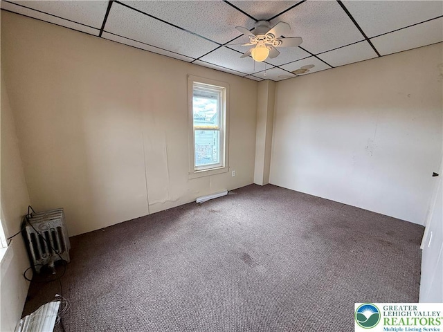 carpeted spare room with a drop ceiling and a ceiling fan