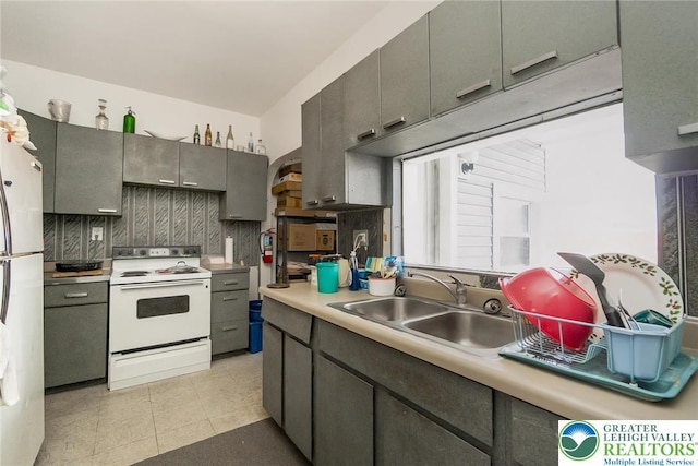kitchen with a sink, light countertops, white appliances, gray cabinetry, and decorative backsplash