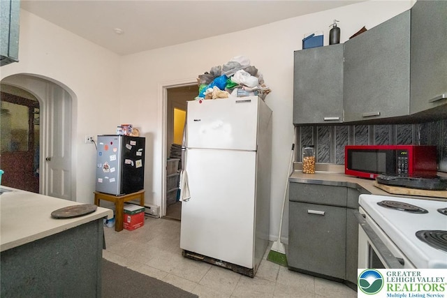 kitchen with baseboard heating, gray cabinets, white appliances, light countertops, and arched walkways