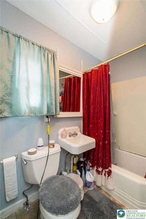 bathroom with a sink, toilet, and shower / tub combo with curtain