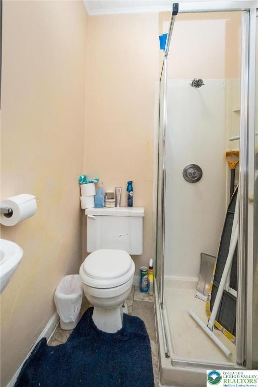 bathroom featuring a shower stall, tile patterned floors, baseboards, and toilet
