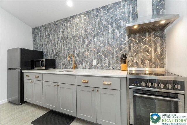 5112 Creek Rd, Heidelberg Twp, PA 18078 - kitchen with wall chimney range hood, light countertops, gray cabinetry, stainless steel appliances, and a sink