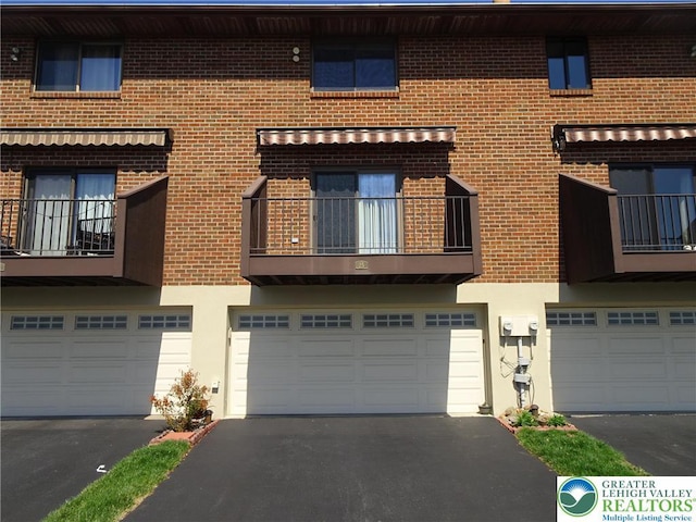 multi unit property with brick siding, a garage, and driveway