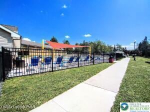 view of swimming pool with fence and a lawn