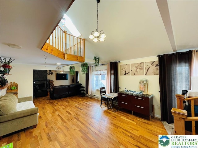living area with high vaulted ceiling, light wood-type flooring, and a chandelier