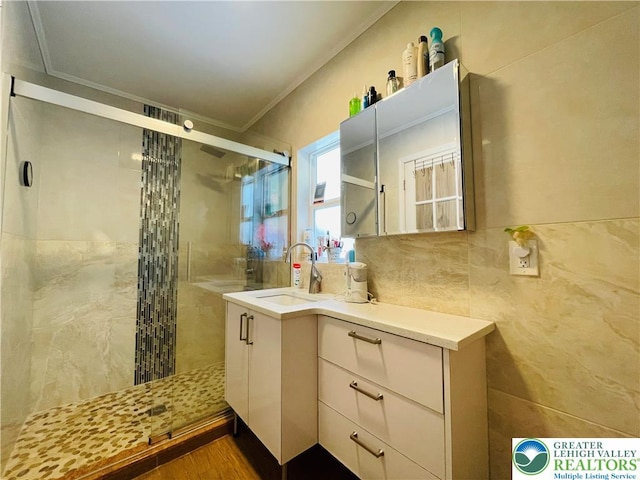 bathroom with vanity, tile walls, crown molding, and a stall shower