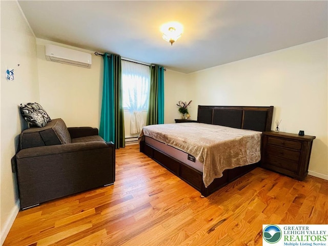 bedroom with baseboards, a wall mounted AC, light wood-style floors, and baseboard heating