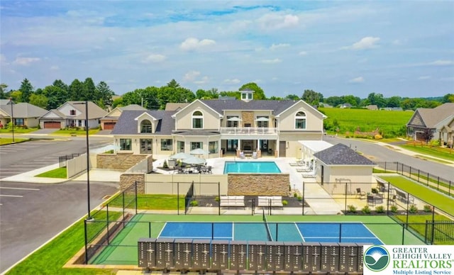 exterior space with fence, a fenced in pool, a balcony, and a tennis court