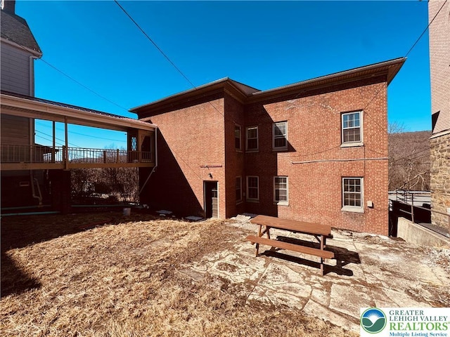 rear view of property with a patio and brick siding