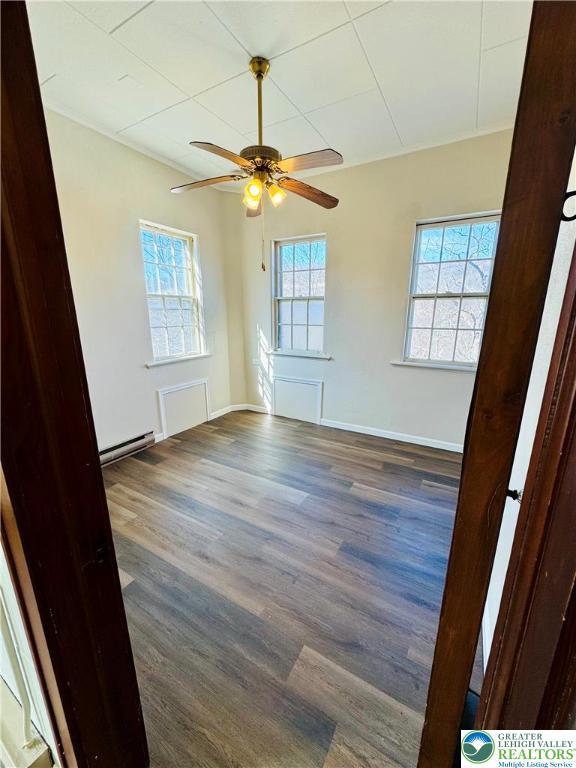 unfurnished room with ceiling fan, wood finished floors, and baseboards