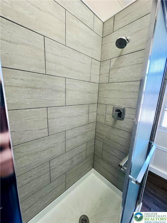 full bath with tiled shower and wood finished floors