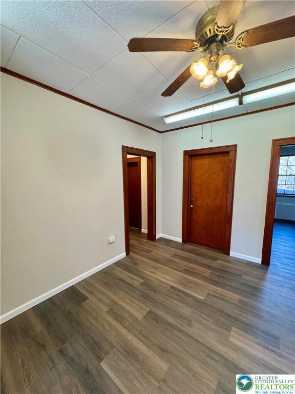 unfurnished bedroom with dark wood-style flooring, baseboards, and ceiling fan