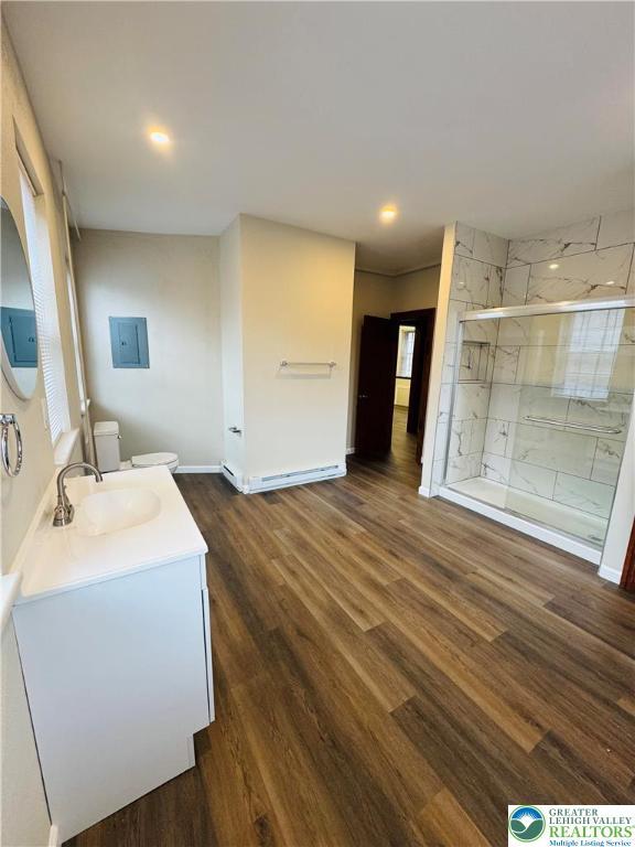 bathroom with vanity, baseboards, a stall shower, toilet, and wood finished floors