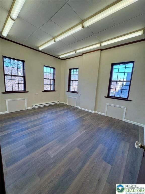 spare room with baseboards, dark wood-style floors, and baseboard heating