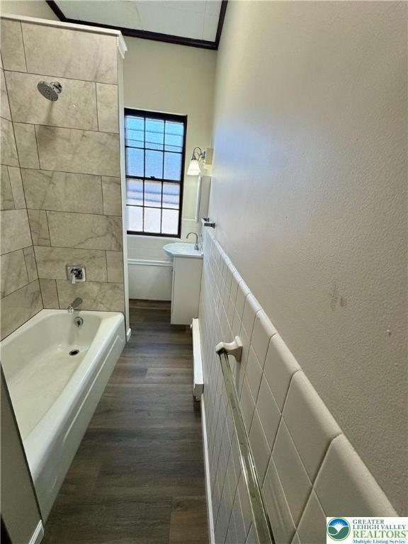 full bathroom featuring wood finished floors, vanity, ornamental molding, and  shower combination