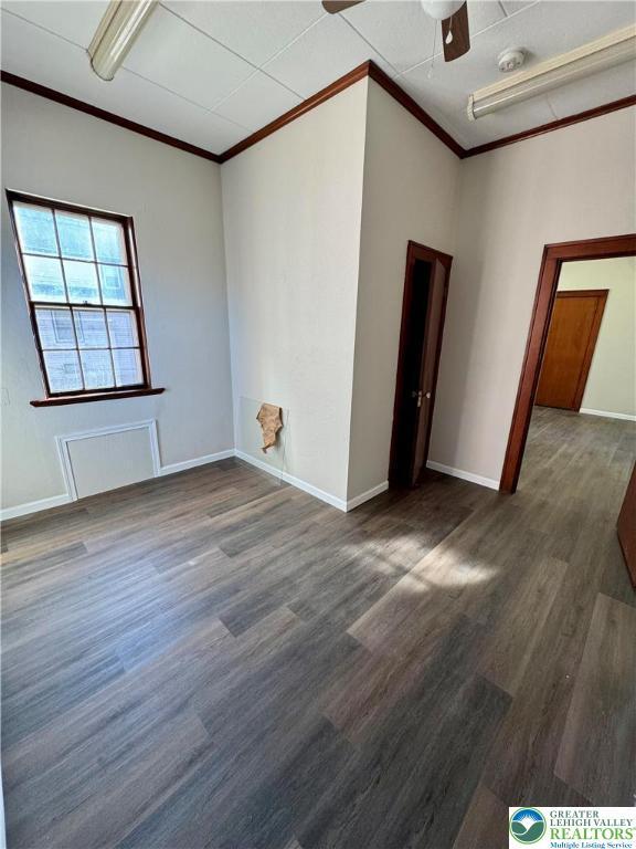empty room featuring crown molding, wood finished floors, ceiling fan, and baseboards
