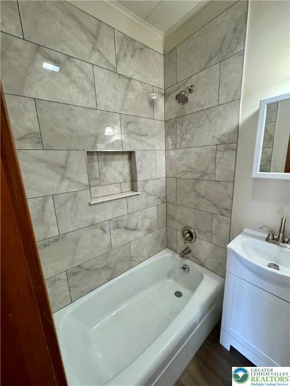 full bath with wood finished floors, tub / shower combination, ornamental molding, and vanity