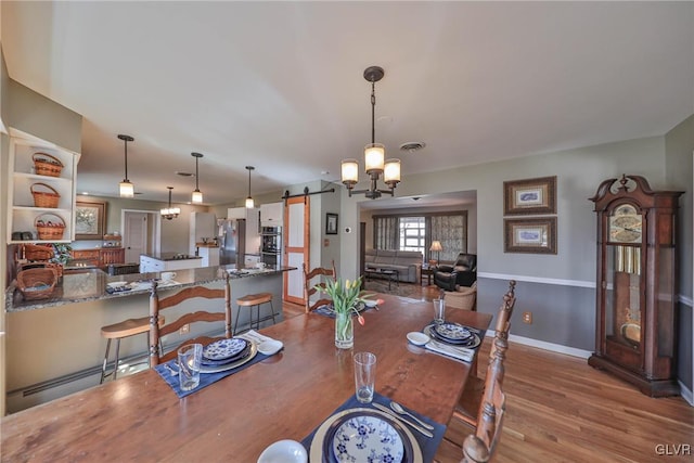 3332 Sherwood Rd, Palmer Twp, PA 18045 - dining space with a barn door, an inviting chandelier, wood finished floors, visible vents, and baseboards