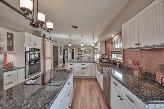 3332 Sherwood Rd, Palmer Twp, PA 18045 - kitchen with a barn door, stainless steel appliances, visible vents, a sink, and white cabinetry