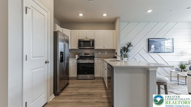 1205 Susan Cir, Upper Macungie Twp, PA 18031 - kitchen with light wood finished floors, a sink, a peninsula, appliances with stainless steel finishes, and a breakfast bar area