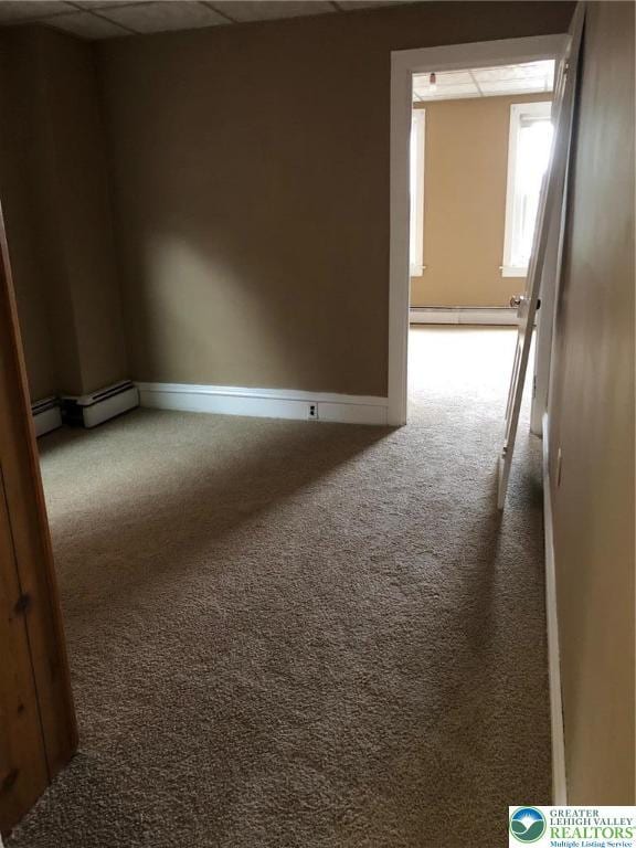 carpeted spare room featuring a paneled ceiling, baseboard heating, and baseboards
