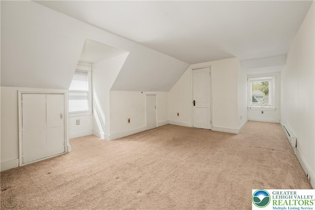 additional living space with lofted ceiling, a baseboard radiator, light colored carpet, and baseboards