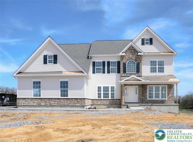 view of front of property with stone siding and roof with shingles