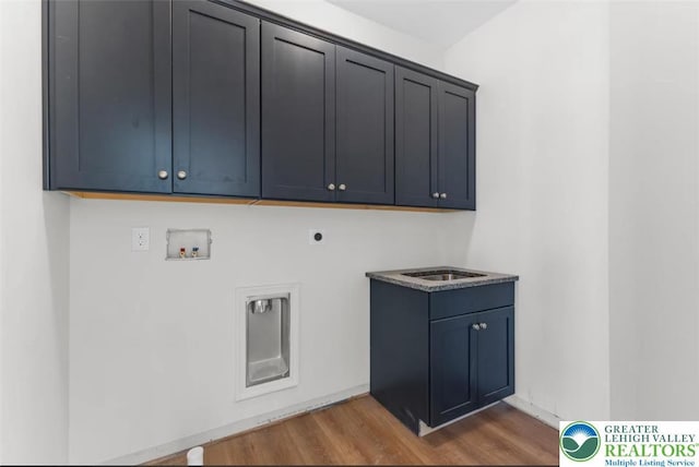 washroom featuring electric dryer hookup, wood finished floors, washer hookup, and cabinet space