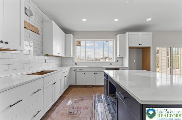 kitchen with decorative backsplash, recessed lighting, white cabinetry, and light countertops