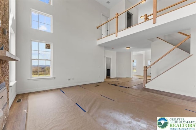 unfurnished living room with a high ceiling, a wealth of natural light, and visible vents