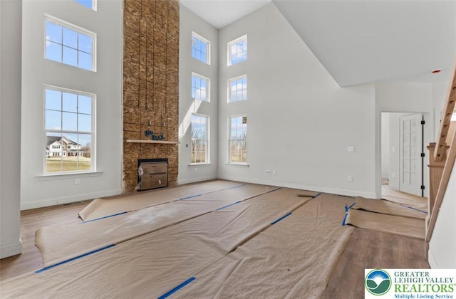 unfurnished living room featuring baseboards, a towering ceiling, and stairs