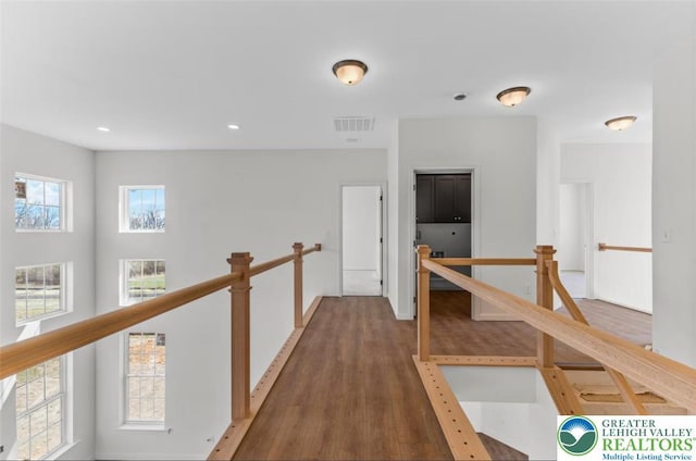 hall featuring recessed lighting, wood finished floors, visible vents, an upstairs landing, and baseboards