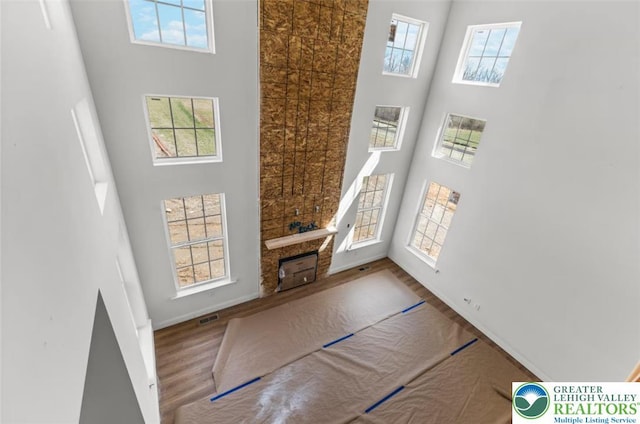 interior space featuring wood finished floors, visible vents, and a towering ceiling