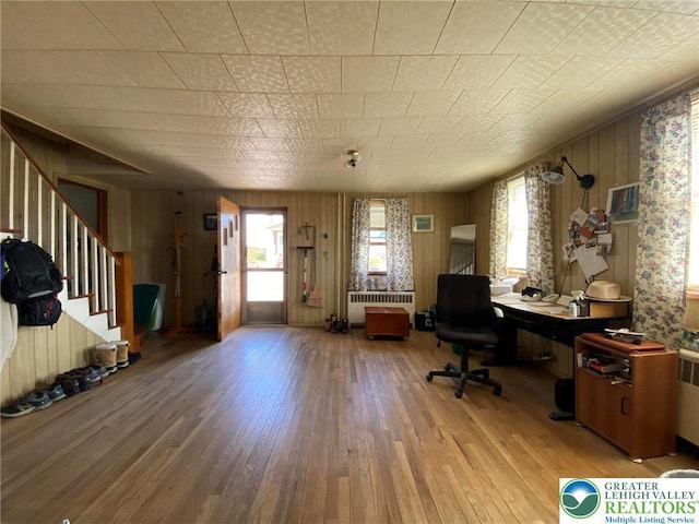 home office with radiator, light wood finished floors, and wood walls