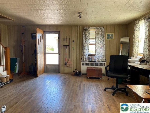 office area with radiator, wooden walls, and wood-type flooring