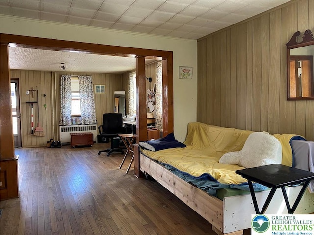 living room with radiator, hardwood / wood-style floors, and wood walls