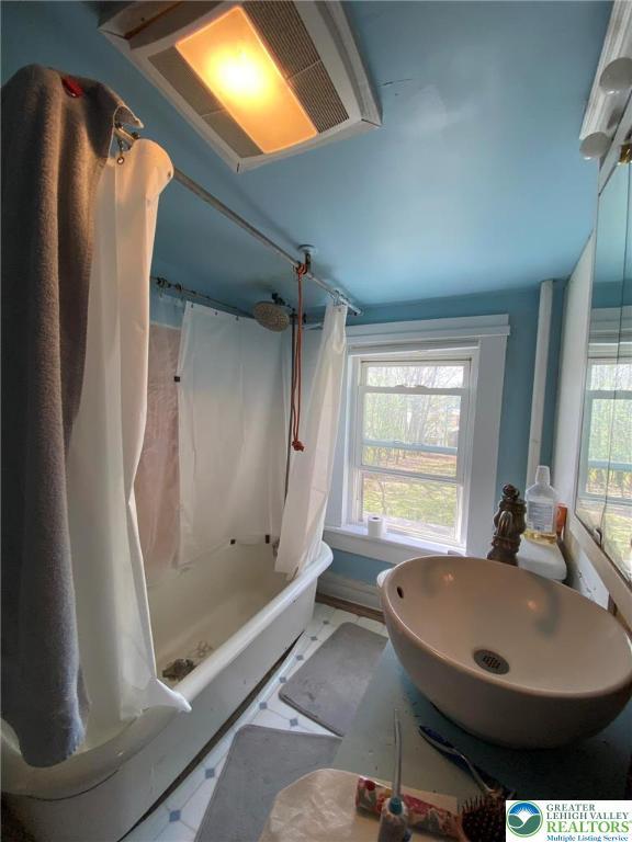 bathroom featuring shower / bath combination with curtain and a sink