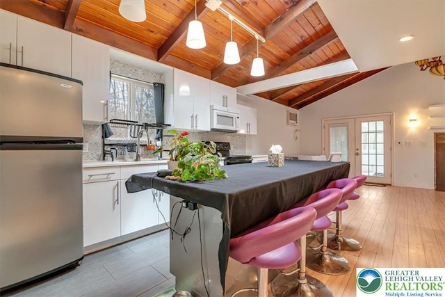 kitchen featuring range with electric cooktop, tasteful backsplash, freestanding refrigerator, wooden ceiling, and white microwave