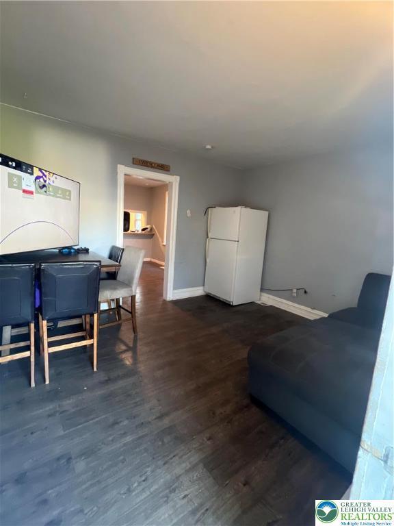 living room with baseboards and dark wood-type flooring
