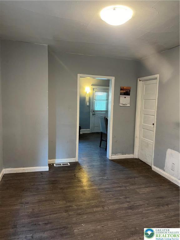 spare room with baseboards and dark wood-style floors