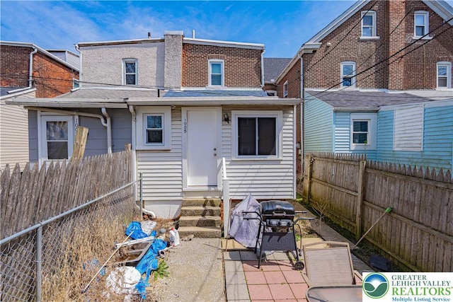 back of property featuring entry steps, a shingled roof, a fenced backyard, and a patio area