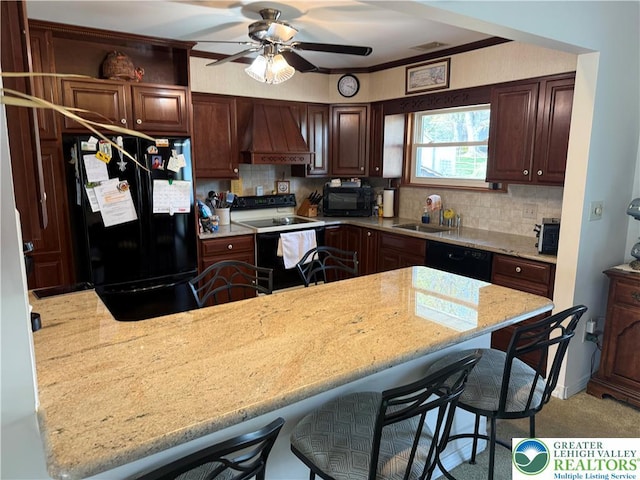 kitchen with decorative backsplash, a breakfast bar, black appliances, ceiling fan, and premium range hood