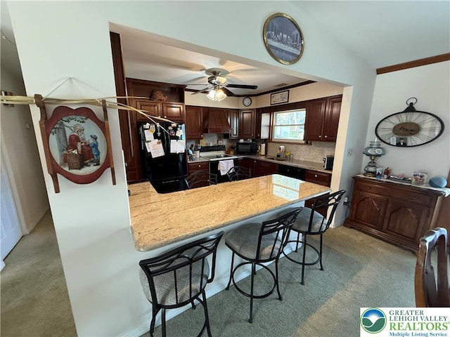 kitchen featuring black appliances, a sink, a peninsula, and light carpet