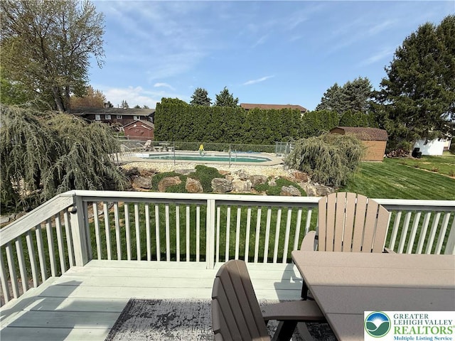 wooden deck featuring a lawn and a fenced in pool