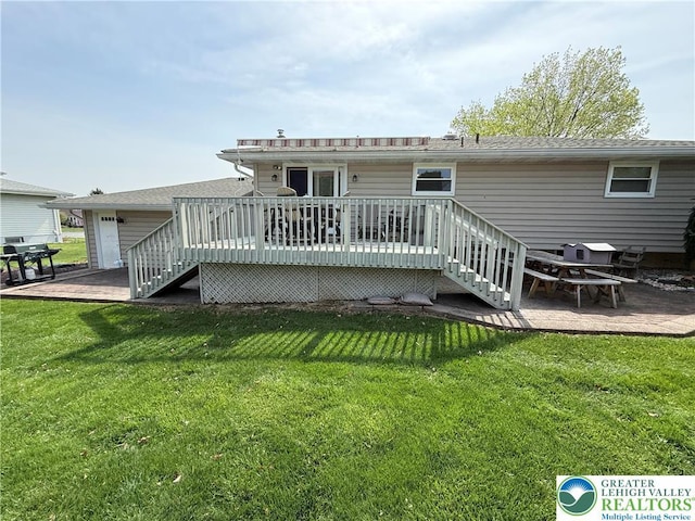 rear view of house featuring a lawn, stairway, a wooden deck, and a garage