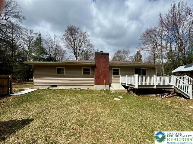 back of house with a deck, a yard, fence, and a chimney