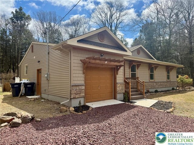 view of front facade with a garage, gravel driveway, and stone siding